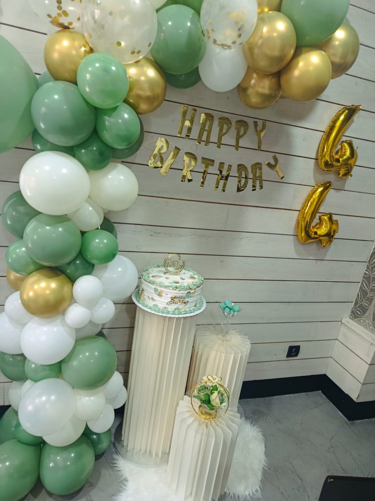 Arco de globos verdes y dorados con tarta de cumpleaños montado en el bar Cononda