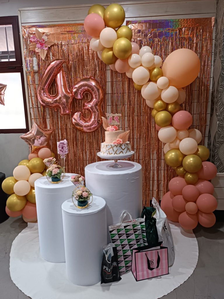 Decoración de cumpleaños con arco de globos y tarta en el bar Cononda